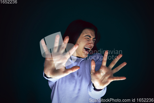 Image of Close up portrait of young crazy scared and shocked woman isolated on dark background