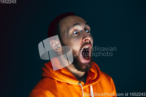 Image of Close up portrait of crazy scared and shocked man isolated on dark background