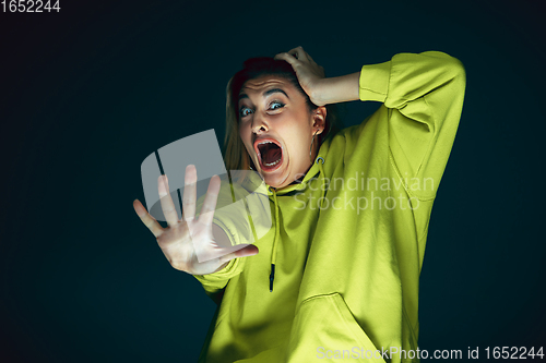 Image of Close up portrait of young crazy scared and shocked woman isolated on dark background