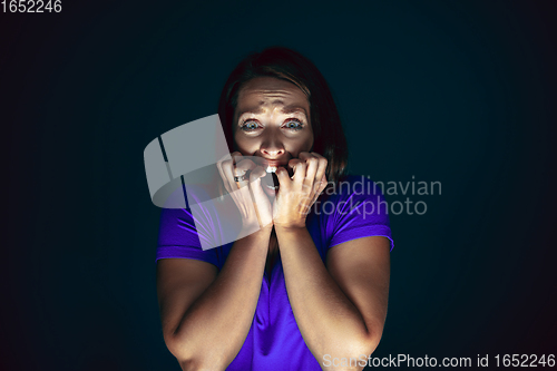 Image of Close up portrait of young crazy scared and shocked woman isolated on dark background