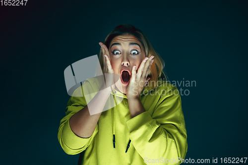 Image of Close up portrait of young crazy scared and shocked woman isolated on dark background