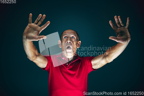 Image of Close up portrait of crazy scared and shocked man isolated on dark background