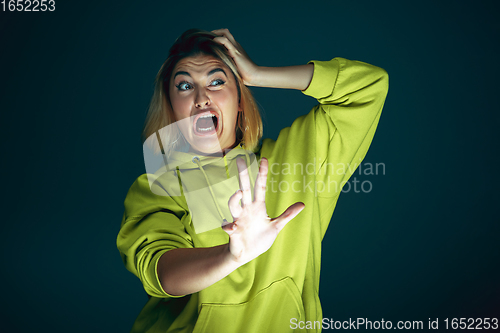 Image of Close up portrait of young crazy scared and shocked woman isolated on dark background