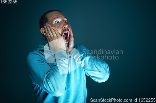 Image of Close up portrait of young crazy scared and shocked man isolated on dark background