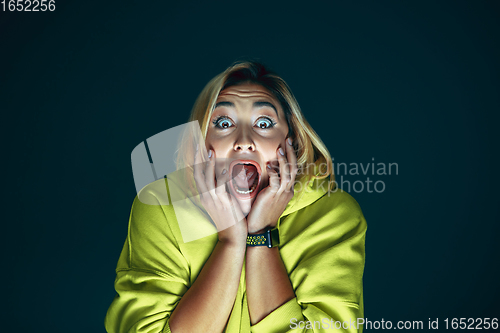 Image of Close up portrait of young crazy scared and shocked woman isolated on dark background