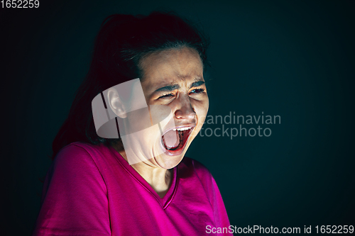 Image of Close up portrait of young crazy scared and shocked woman isolated on dark background