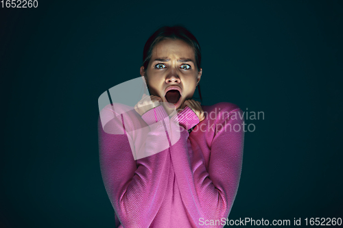 Image of Close up portrait of young crazy scared and shocked woman isolated on dark background