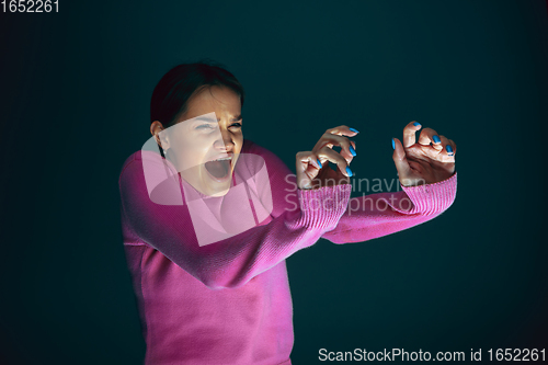 Image of Close up portrait of young crazy scared and shocked woman isolated on dark background