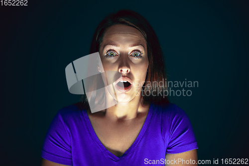 Image of Close up portrait of young crazy scared and shocked woman isolated on dark background