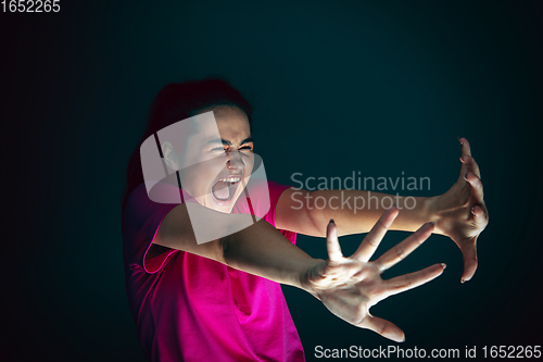 Image of Close up portrait of young crazy scared and shocked woman isolated on dark background