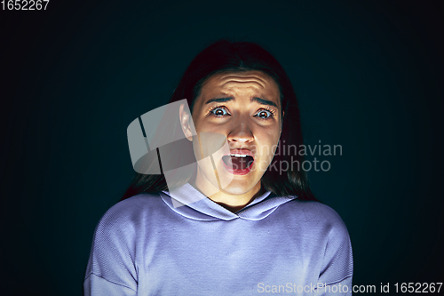 Image of Close up portrait of young crazy scared and shocked woman isolated on dark background