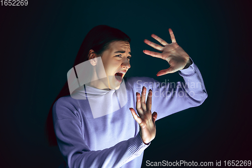 Image of Close up portrait of young crazy scared and shocked woman isolated on dark background