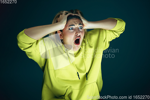 Image of Close up portrait of young crazy scared and shocked woman isolated on dark background