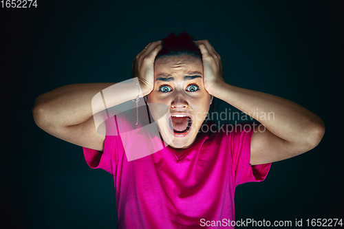 Image of Close up portrait of young crazy scared and shocked woman isolated on dark background