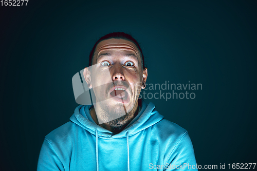 Image of Close up portrait of young crazy scared and shocked man isolated on dark background