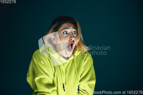 Image of Close up portrait of young crazy scared and shocked woman isolated on dark background