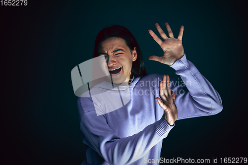 Image of Close up portrait of young crazy scared and shocked woman isolated on dark background