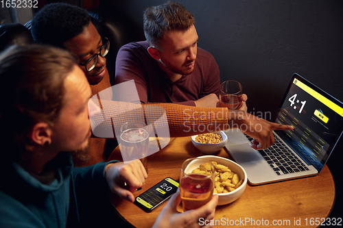 Image of Excited fans with mobile app for betting and score on their devices. Gambling, emotions