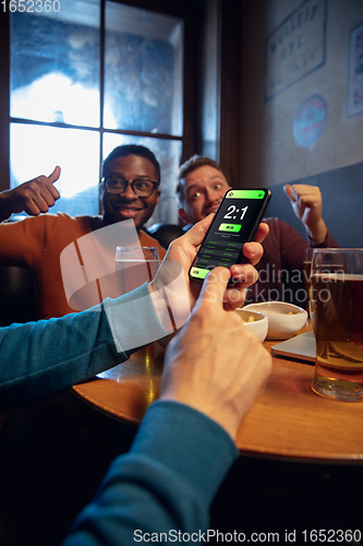 Image of Excited fans with mobile app for betting and score on their devices. Gambling, emotions