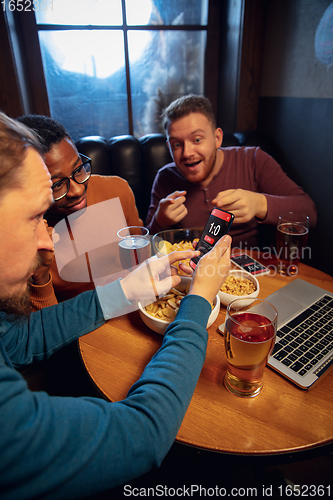 Image of Excited fans with mobile app for betting and score on their devices. Gambling, emotions