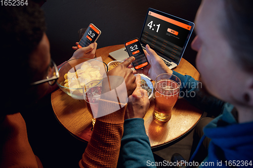 Image of Excited fans with mobile app for betting and score on their devices. Gambling, emotions