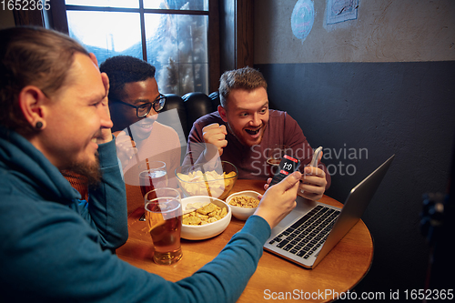 Image of Excited fans with mobile app for betting and score on their devices. Gambling, emotions