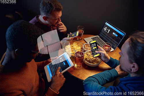 Image of Excited fans with mobile app for betting and score on their devices. Gambling, emotions