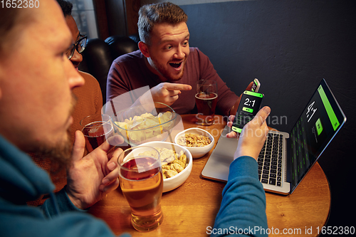 Image of Excited fans with mobile app for betting and score on their devices. Gambling, emotions