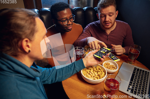 Image of Excited fans with mobile app for betting and score on their devices. Gambling, emotions