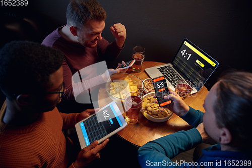 Image of Excited fans with mobile app for betting and score on their devices. Gambling, emotions