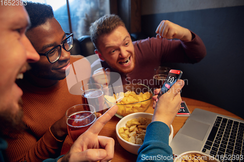 Image of Excited fans with mobile app for betting and score on their devices. Gambling, emotions