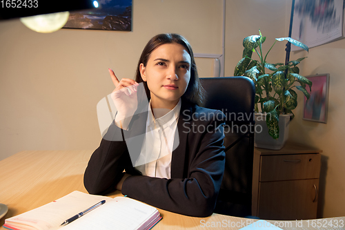 Image of Young woman talking, working during videoconference with colleagues at home