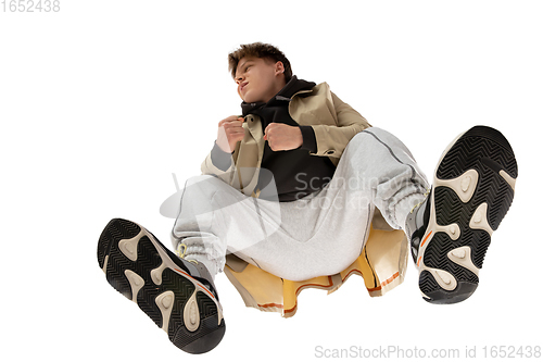 Image of Young stylish man in modern street style outfit isolated on white background, shot from the bottom