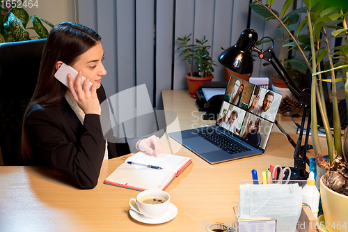 Image of Young woman talking, working during videoconference with colleagues at home