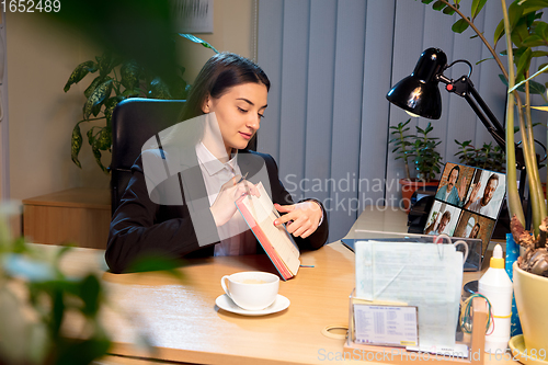 Image of Young woman talking, working during videoconference with colleagues at home