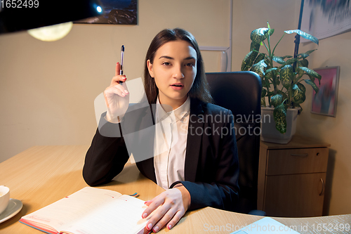Image of Young woman talking, working during videoconference with colleagues at home