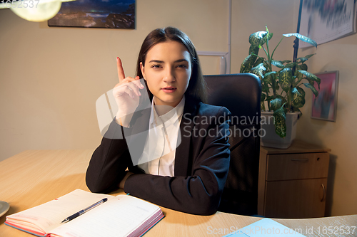 Image of Young woman talking, working during videoconference with colleagues at home