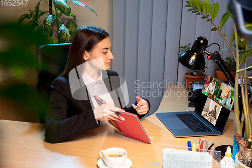 Image of Young woman talking, working during videoconference with colleagues at home