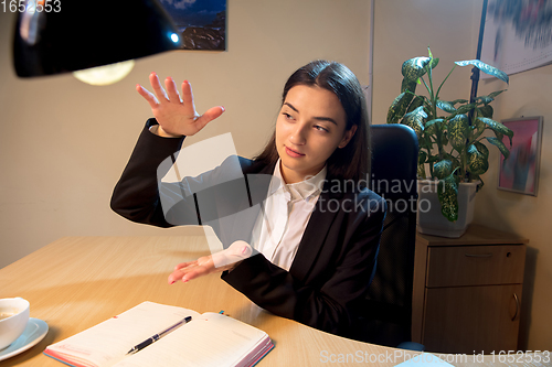 Image of Young woman talking, working during videoconference with colleagues at home