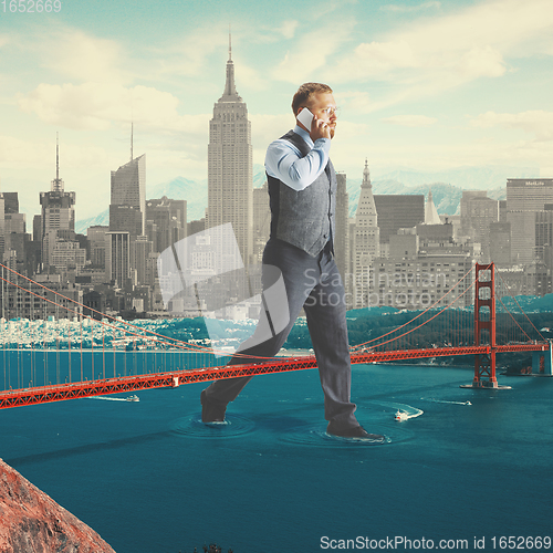 Image of Office worker, huge businessman heading to work on the river through the bridge with megapolis on the background