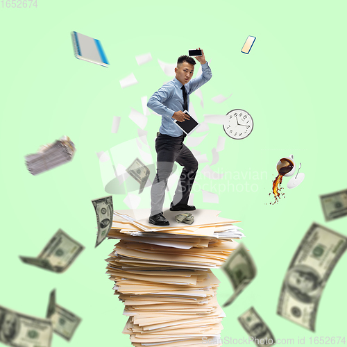 Image of Office worker, businessman, sportsman fighting with deadlines standing on the bunch of documents