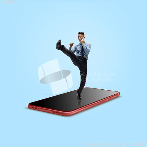 Image of Office worker, businessman fighting on the surface of smartphone\'s screen isolated on background