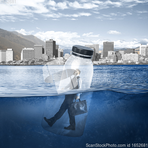 Image of Office worker, businessman closed in bottle heading to work on the river with megapolis on the background