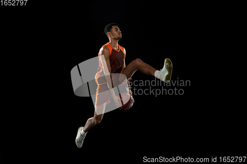 Image of Young african basketball player training on black studio background.