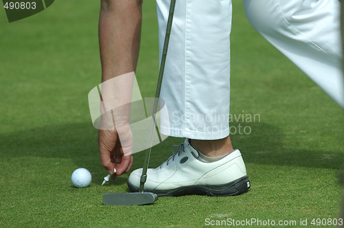 Image of golfer placing golf ball on a tee