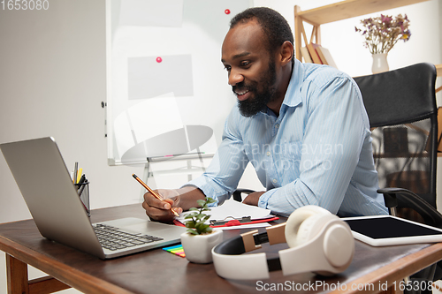 Image of Online english courses at home. Smiling man teaches students remotely in interior of living room