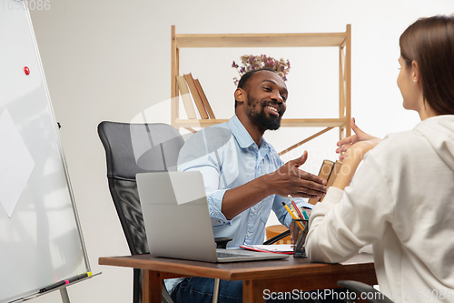 Image of English courses at home. Smiling man teaches student in interior of living room