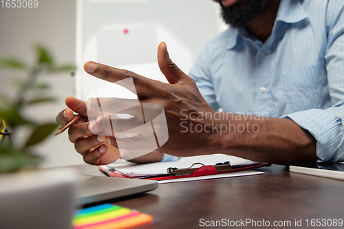 Image of Online english courses at home. Close up hands of man during teaching students remotely in interior of living room