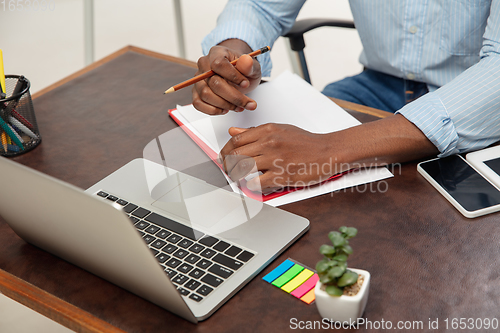 Image of Online english courses at home. Close up hands of man during teaching students remotely in interior of living room