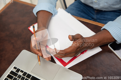 Image of Online english courses at home. Close up hands of man during teaching students remotely in interior of living room